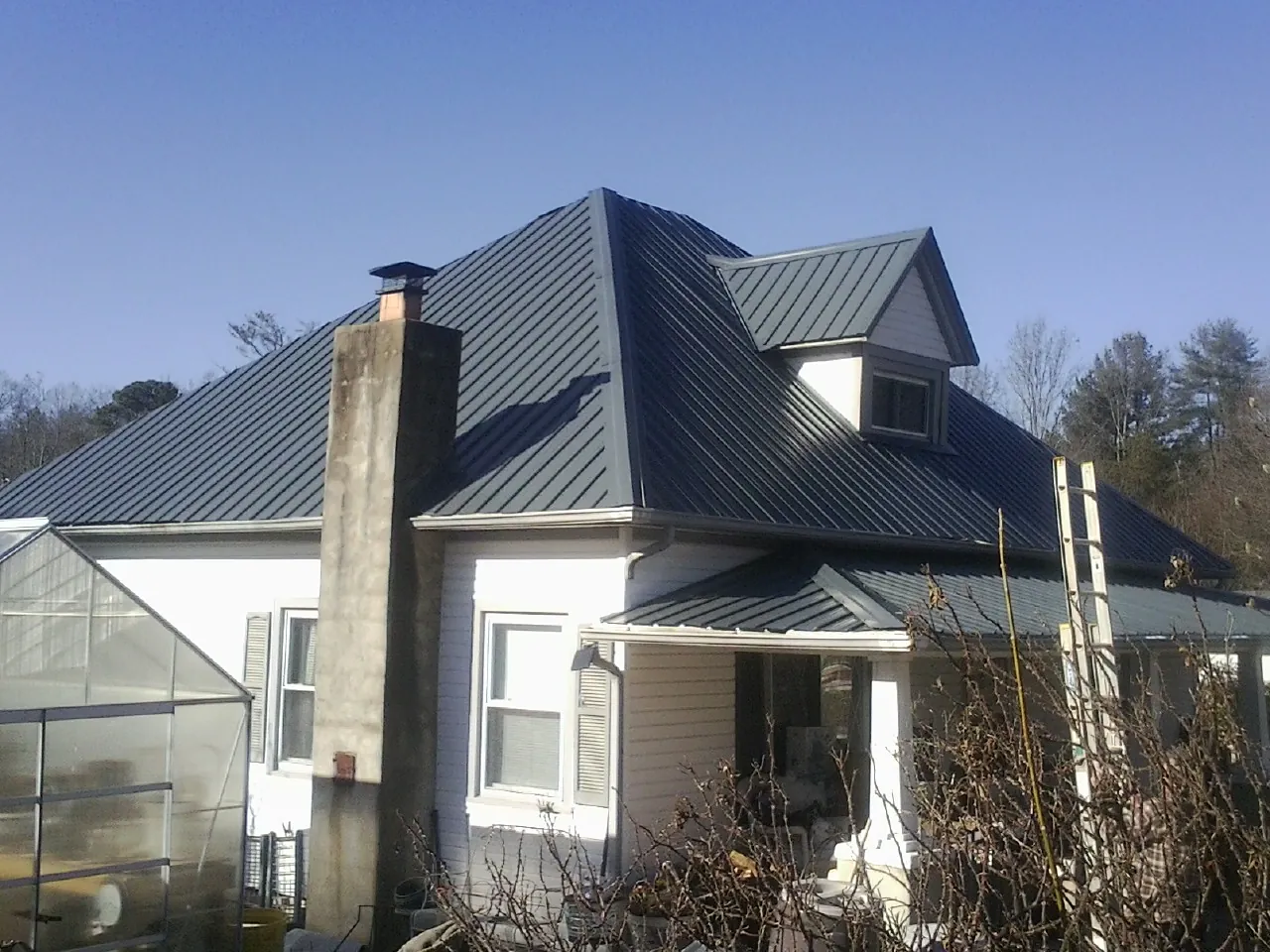 Dark blue standing seam metal roof on a white farmhouse with dormer — Slate & Tile Roof Repair by Roofing Brothers in Westmoreland
