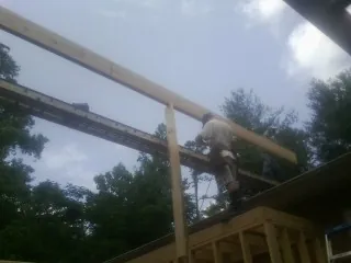 Carpenter setting a ridge beam over a new addition frame in Westmoreland