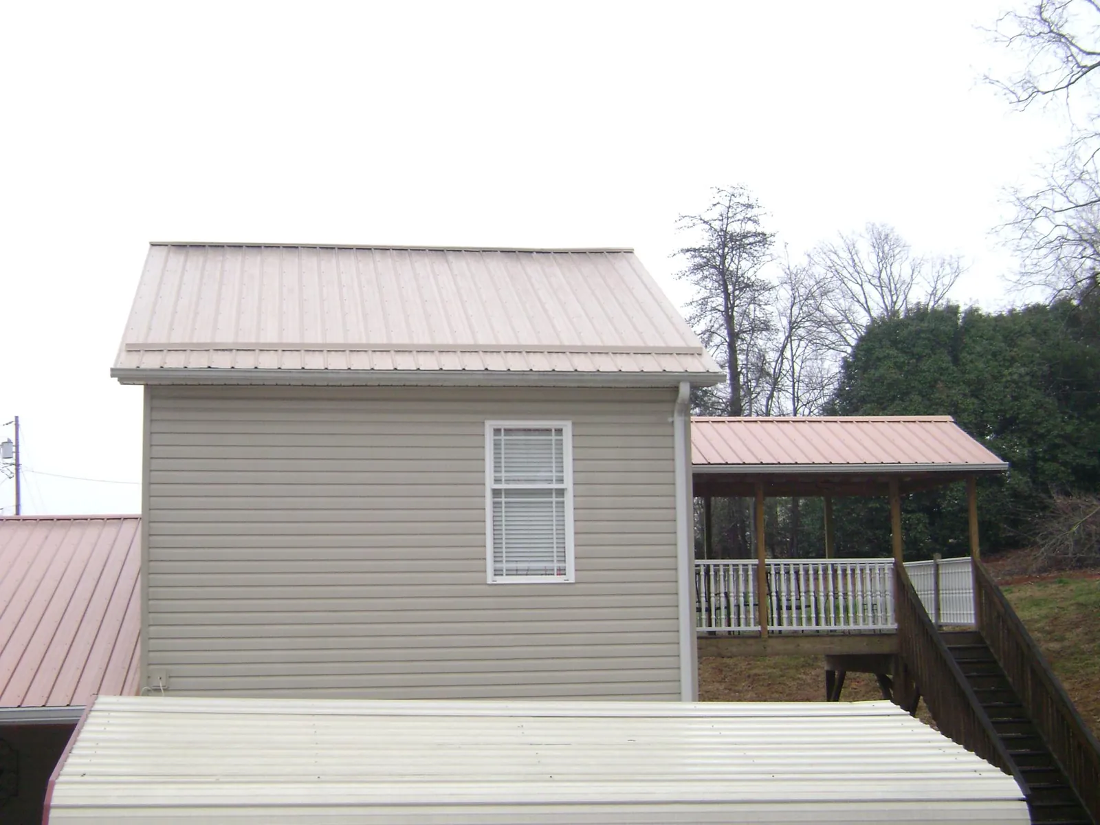 Tan metal roofs on a two story addition and attached porch, from a Roof Replacement job in Westmoreland