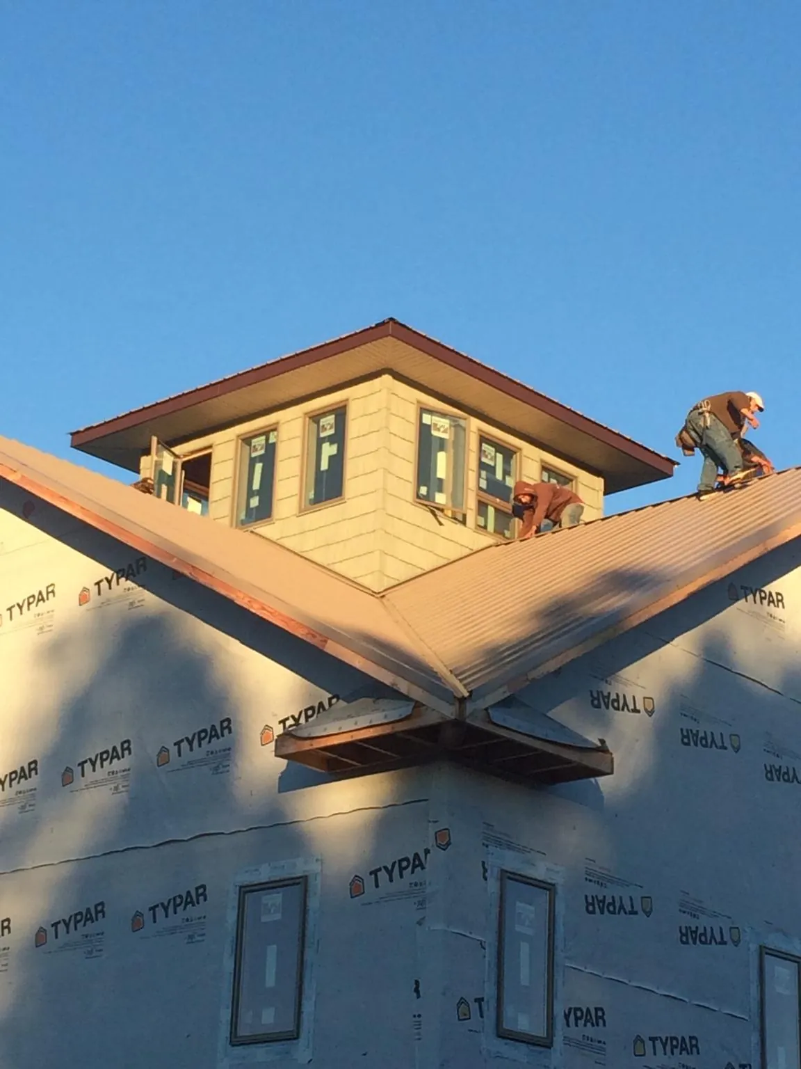 Roofers working around a rooftop cupola on a new metal roof at sunset — Roof Waterproofing in Westmoreland by Roofing Brothers
